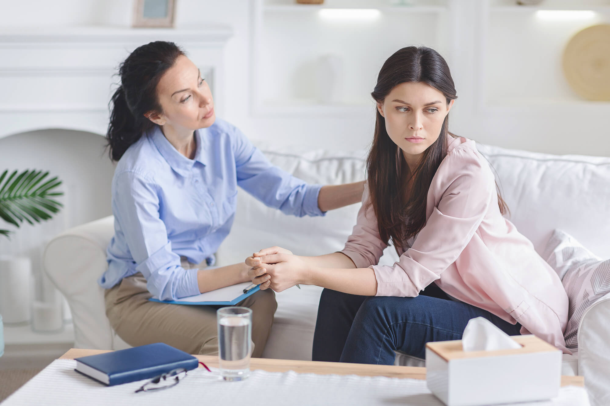 psychologist-comforting-sad-female-patient-in-offi-9RMJ32S.jpg